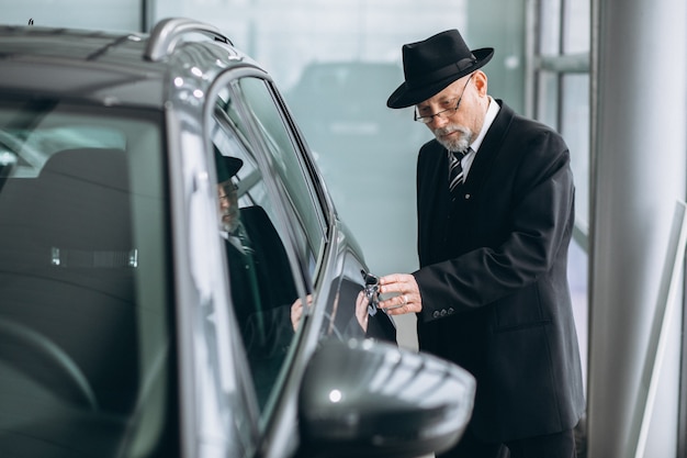 Hogere mens in een autotoonzaal die een auto kiest