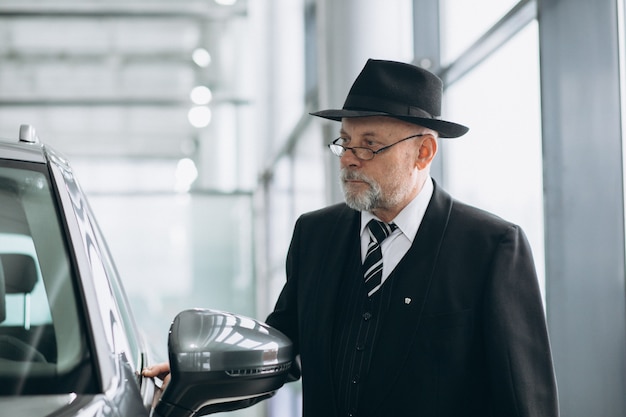 Hogere mens in een autotoonzaal die een auto kiest