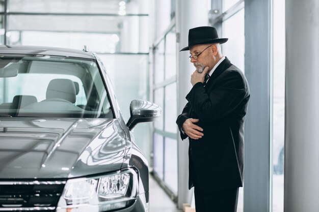 Hogere mens in een autotoonzaal die een auto kiest