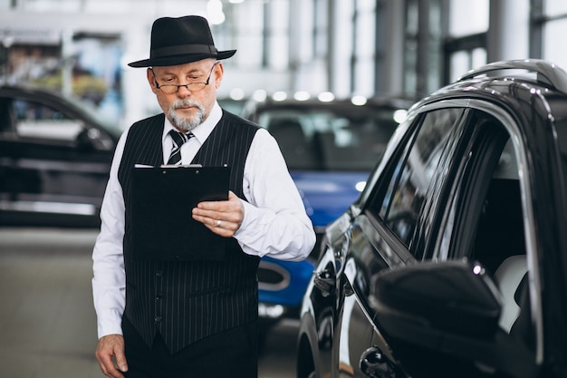 Hogere mens in een autotoonzaal die een auto kiest