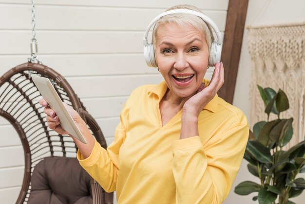 Hogere smileyvrouw die aan muziek hoewel hoofdtelefoons luistert