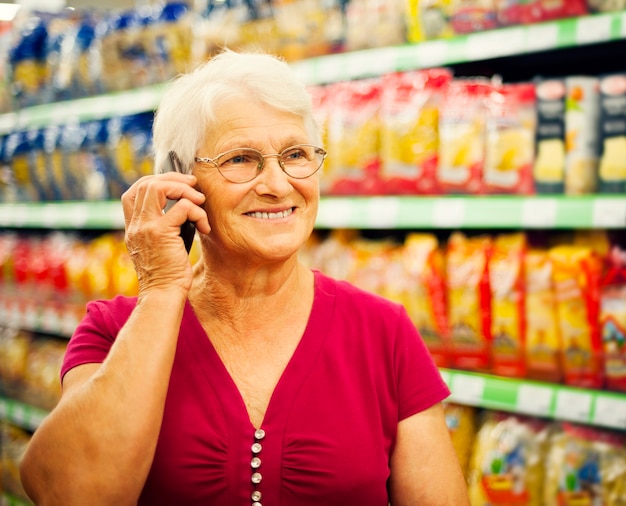 Hogere vrouw aan de telefoon bij supermarkt