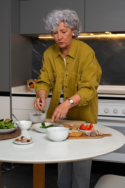 Hogere vrouw die schotel met vijgen in de keuken maakt