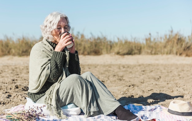 Hogere vrouw het drinken koffie in openlucht