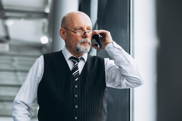 Hogere zakenman die op de telefoon op het kantoor spreekt