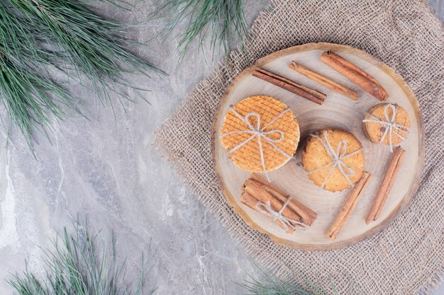 Holland wafels en koekjes op een houten bord met kaneelstokjes rond.
