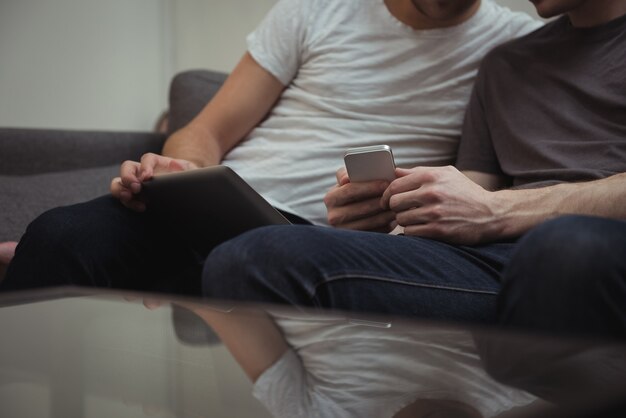 Homo paar zittend op de bank en kijken naar digitale tablet