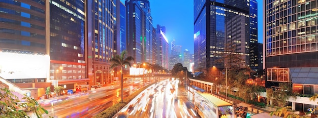 Hong Kong straatpanorama met druk verkeer en wolkenkrabberkantoor in de schemering.