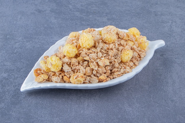 Honingmaïsring met muesli in een bord, op de marmeren tafel.