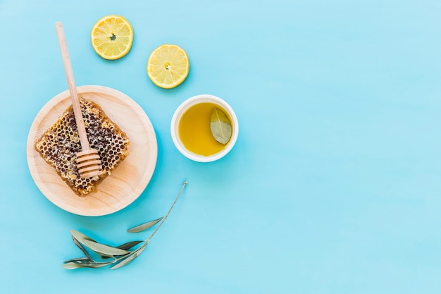 Honingraat, citroenplak met lepel en olie op gekleurde achtergrond