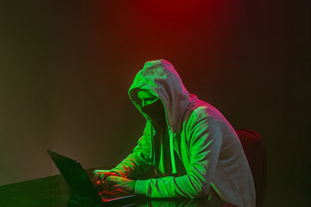 Hooded computerhakker die informatie met laptop steelt