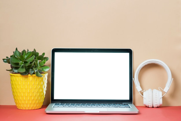 Gratis foto hoofdtelefoons en plant in de buurt van laptop