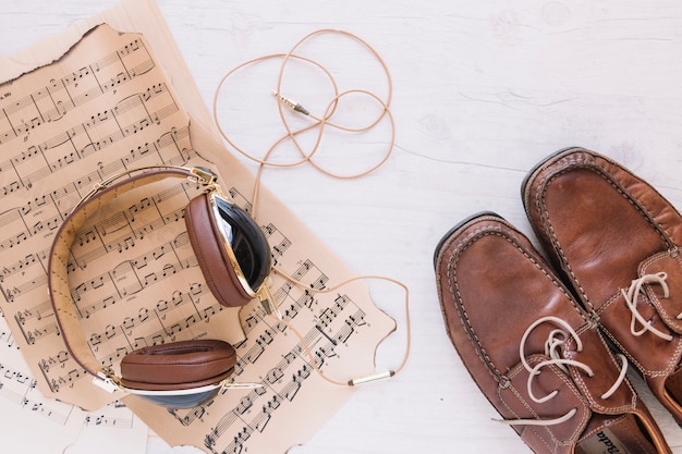 Hoofdtelefoons en schoenen in de buurt van bladmuziek
