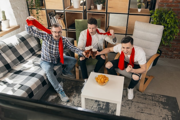 Hoog gespannen. Groep vrienden kijken naar sport match samen in bar. Emotionele fans juichen voor favoriete team, voetbal. Concept van vriendschap, vrijetijdsbesteding, emoties. Wedden, financiën, plezier.