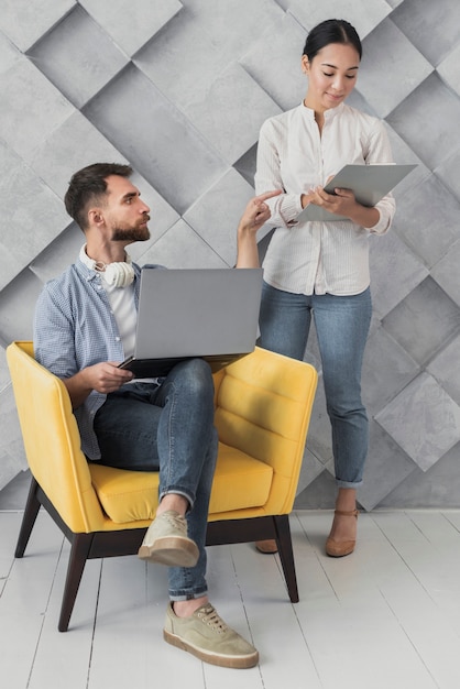 Hoog hoekmannetje op stoel die met collega spreekt