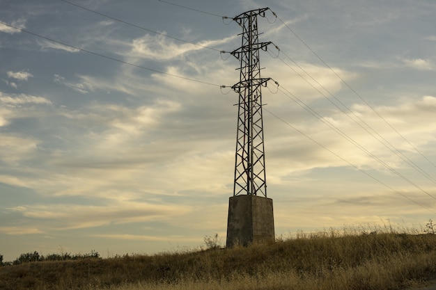 Hoogspanning elektrische transmissietoren tegen de hemel bij zonsopgang
