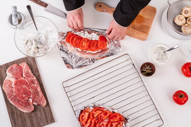 Hoogste mening die van chef-kok schotel met vlees en tomaten voorbereiden