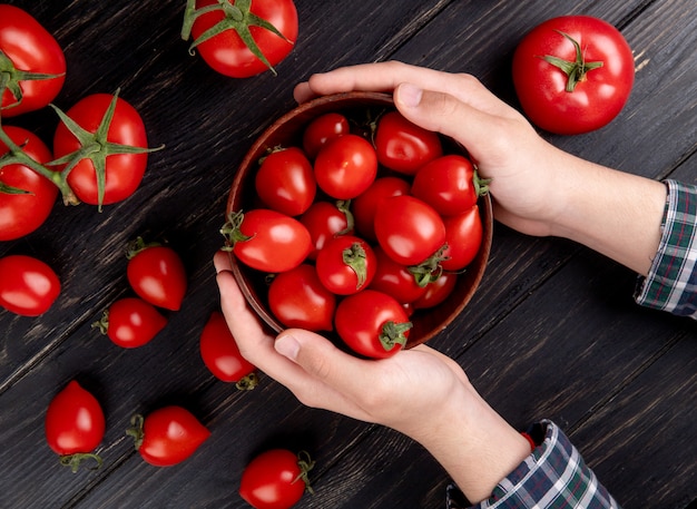 Gratis foto hoogste mening die van vrouwenhanden kom tomaten met andere op houten lijst houden