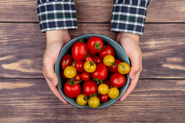 Gratis foto hoogste mening die van vrouwenhanden kom tomaten op houten lijst houden