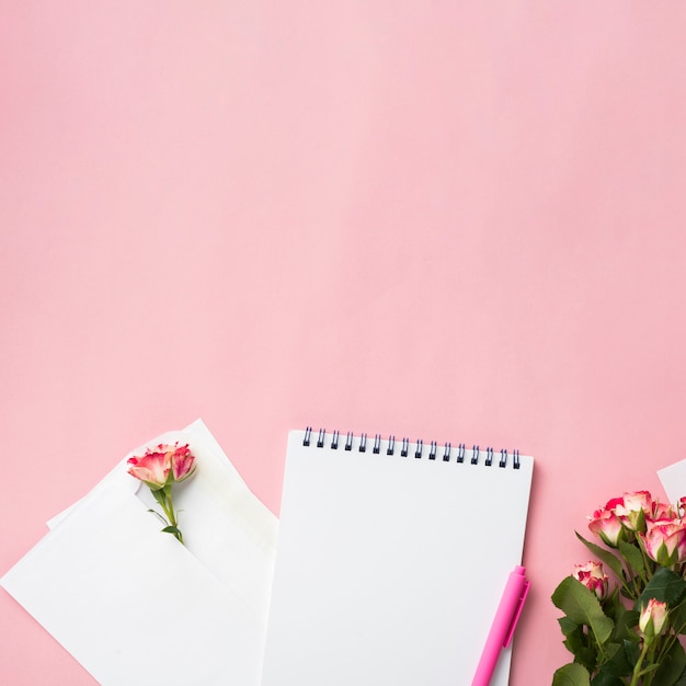 Hoogste mening over notitieboekje op bureau met boeket van rozen en exemplaarruimte