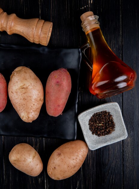 Hoogste mening van aardappels in plaat met zwarte peperzaden smolt boterzout op hout