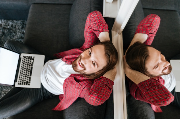 Hoogste mening van de gelukkige ontspannen mens die laptop thuis met behulp van