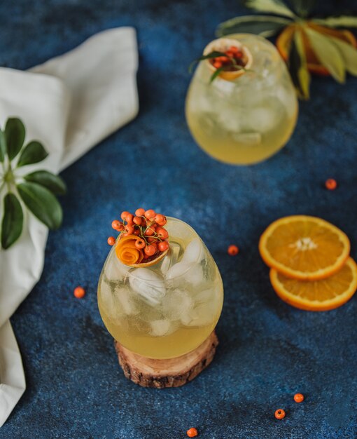 Hoogste mening van de herfstcocktail met duindoorn en jus d'orange in glazen op blauwe muur