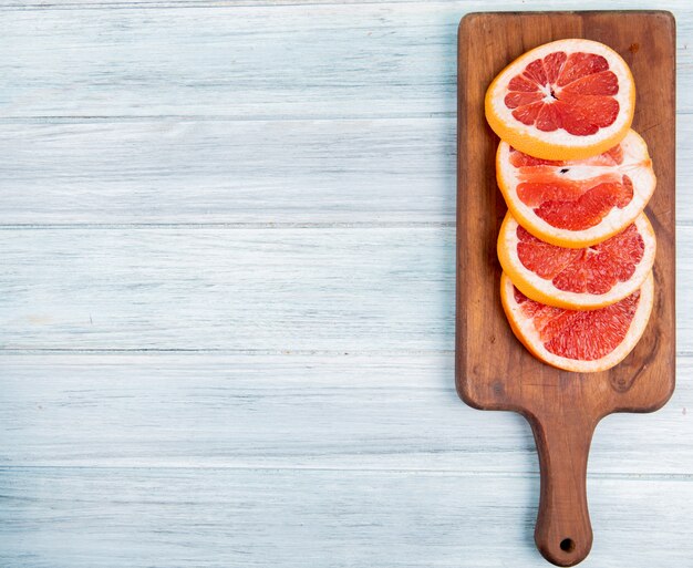 Hoogste mening van grapefruitplakken op scherpe raad aan rechterkant en houten achtergrond met exemplaarruimte