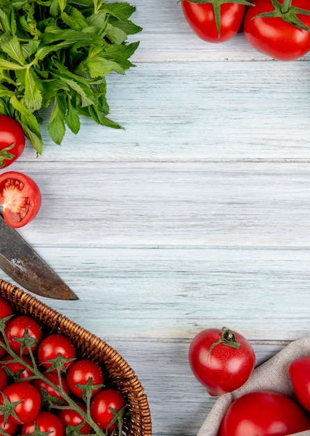 Hoogste mening van groenten als bladeren van de tomaten groene munt met mes op houten oppervlakte met exemplaarruimte