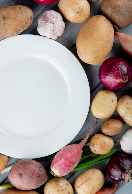 Gratis foto hoogste mening van groenten als de uiradijs van de knoflookaardappel met lege plaat op houten achtergrond