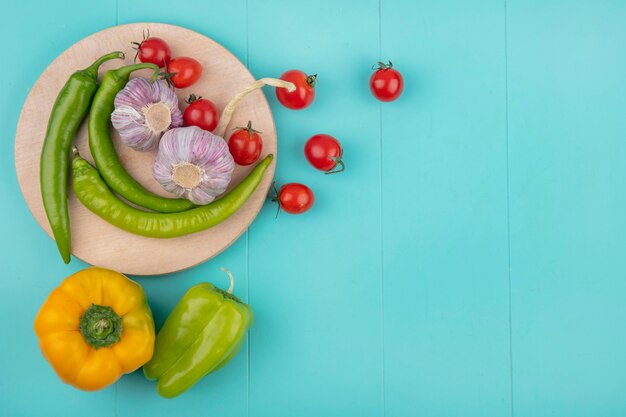 Hoogste mening van groenten als tomaat van de knoflookpeper op scherpe raad op blauwe oppervlakte