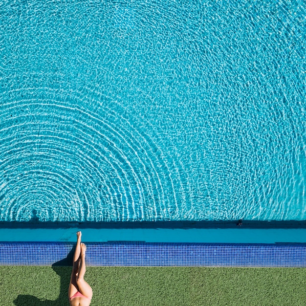 Hoogste mening van meisje het ontspannen naast pool