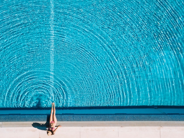 Hoogste mening van meisje het ontspannen naast pool