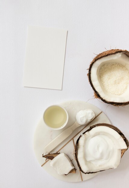 Hoogste mening van schoonheidsmiddel met kokosnoot en lege kaart op witte oppervlakte