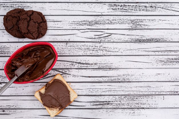 Hoogste mening van toost met chocolade en koekjes en exemplaarruimte op witte houten horizontale achtergrond