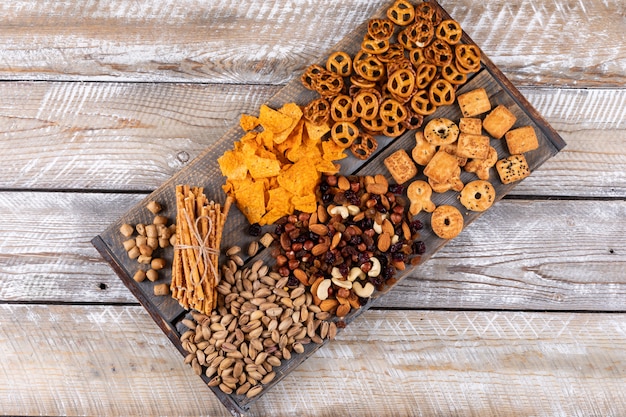 Hoogste mening van verschillend soort snacks als noten, crackers en koekjes op witte houten horizontale oppervlakte