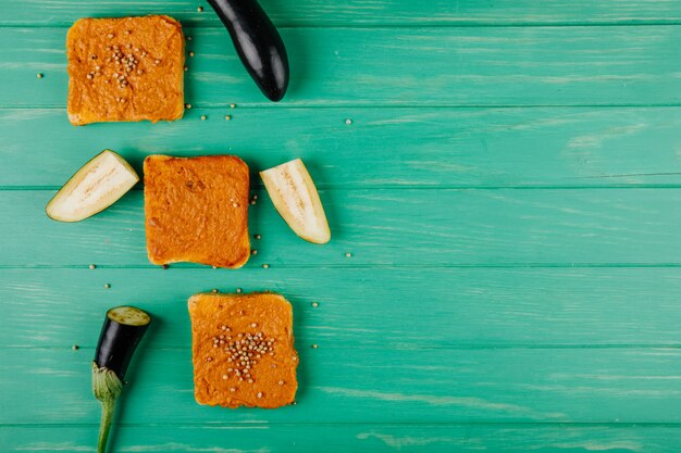 Hoogste mening van vierkante die broodplakken met auberginekaviaar worden gepleisterd met peperkorrels wordt bedekt op groene houten achtergrond met exemplaarruimte