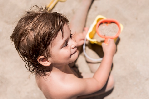 Hoogste menings dichte omhooggaand schot van een jong geitje het spelen met zand