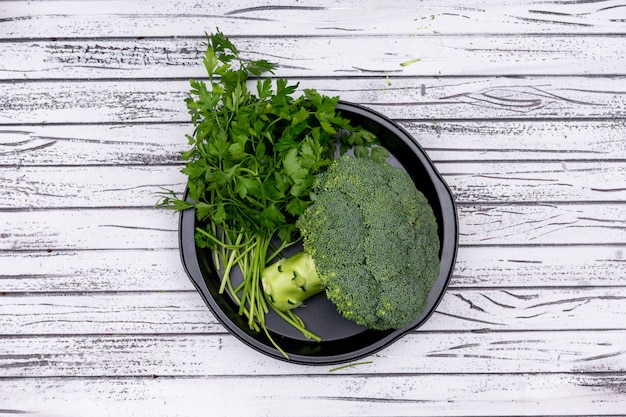 Hoogste meningspeterselie en broccoli in zwarte kom op houten