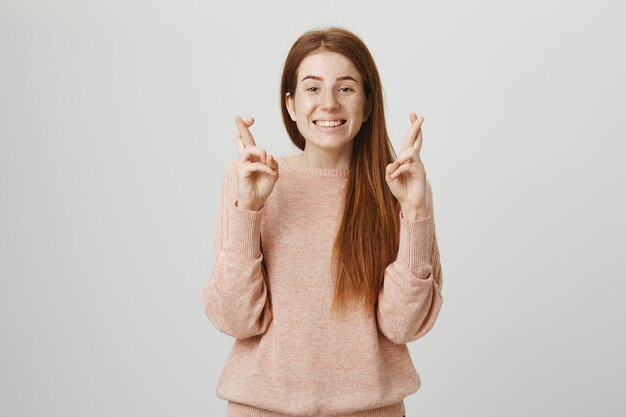 Hoopvol mooi roodharig meisje kruis vingers veel succes