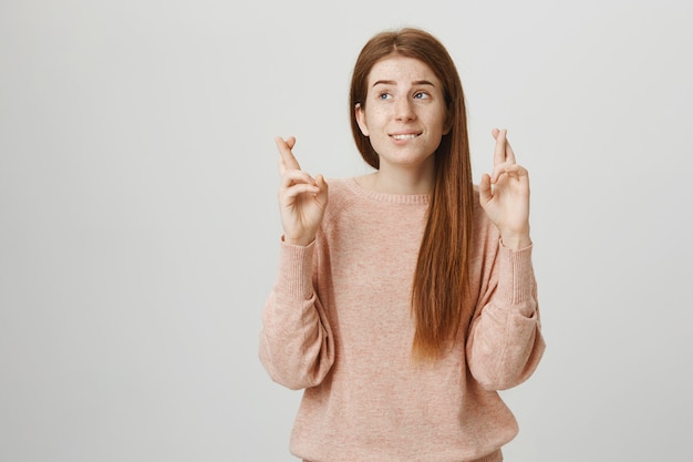 Hoopvol mooi roodharig meisje kruis vingers veel succes