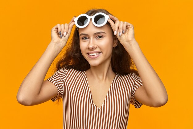 Horizontaal portret van schattige charmante jonge vrouw stijlvolle gestreepte jurk dragen