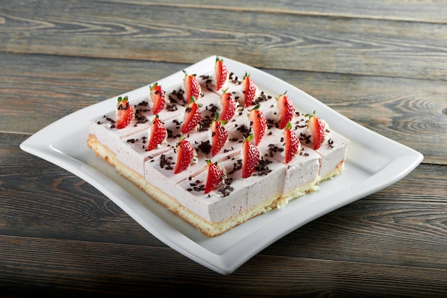 Gratis foto horizontaal schot van vers gebakken heerlijke cheesecake versierd met aardbeien op de bovenste houten tafel gebak koken bakken dessert ontbijt zoete concept.