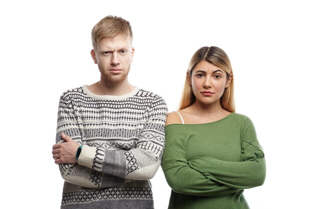 Horizontaal schot van wantrouwend jong koppel dat de armen kruist en staart, met twijfelachtige sceptische blikken. Menselijke gezichtsuitdrukkingen, emoties, gevoelens, houding en lichaamstaal