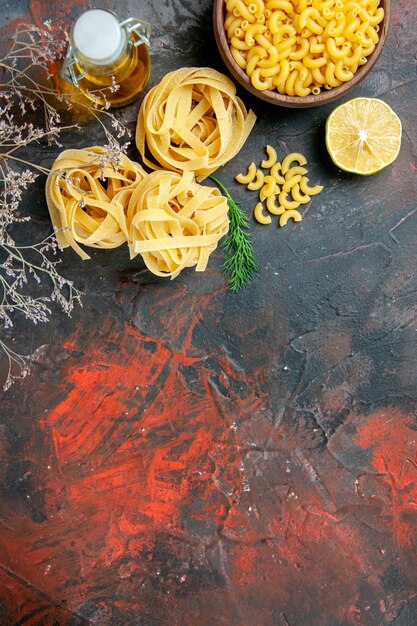 Horizontale weergave van drie ongekookte porties spaghetti en groene oliefles op de top van de gemengde kleurentabel