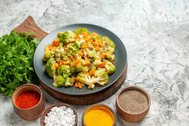 Horizontale weergave van gezonde plantaardige salade verschillende kruiden en een bos van groen op witte tafel