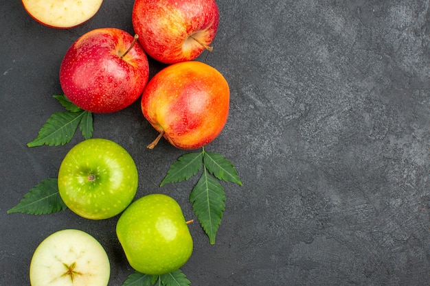 Horizontale weergave van hele en gesneden verse rode appels en bladeren aan de rechterkant op zwarte achtergrond