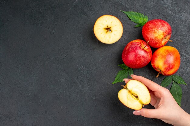 Horizontale weergave van hele en gesneden verse rode appels en bladeren op zwarte achtergrond