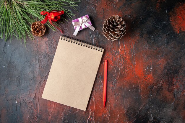 Horizontale weergave van spiraalvormige notebook pen conifer kegel cadeau en cadeau op donkere achtergrond