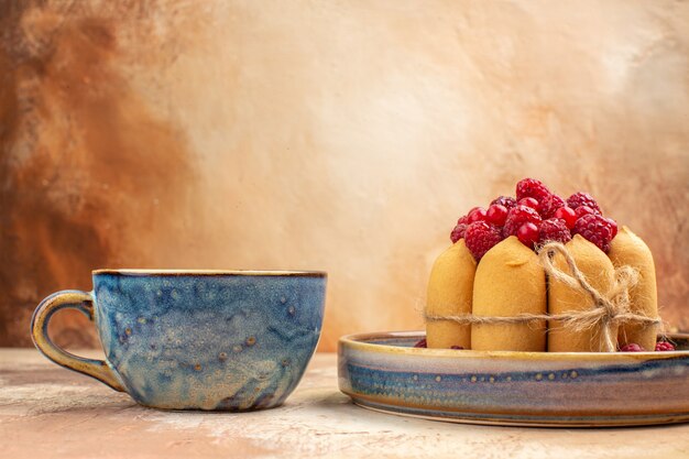 Horizontale weergave van vers gebakken zachte cake met fruit en thee in een blauwe kop op gemengde kleurentafel